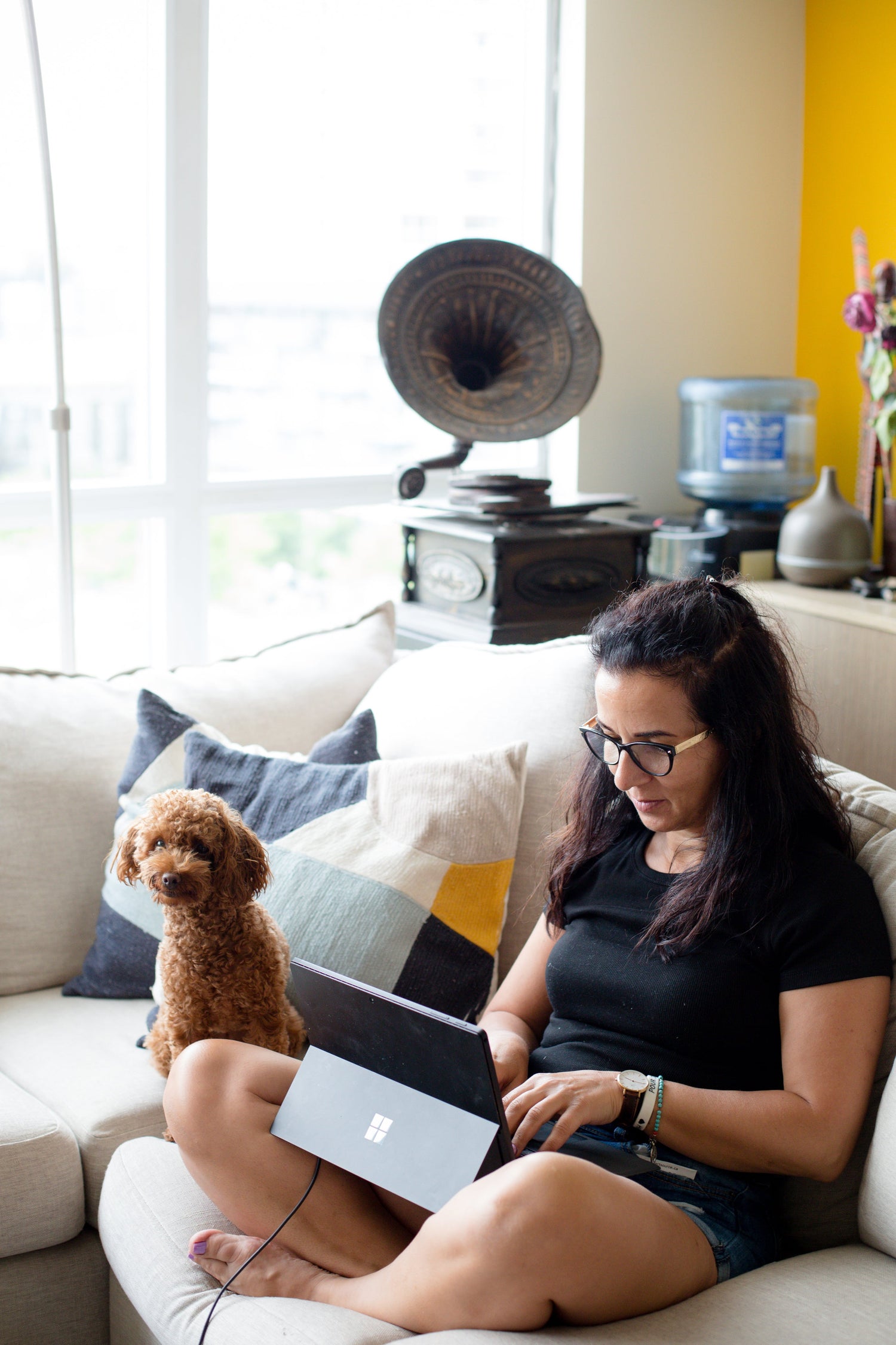 woman sitting with her laptop and dog on her couch doing work on ndis policy and procedure templates